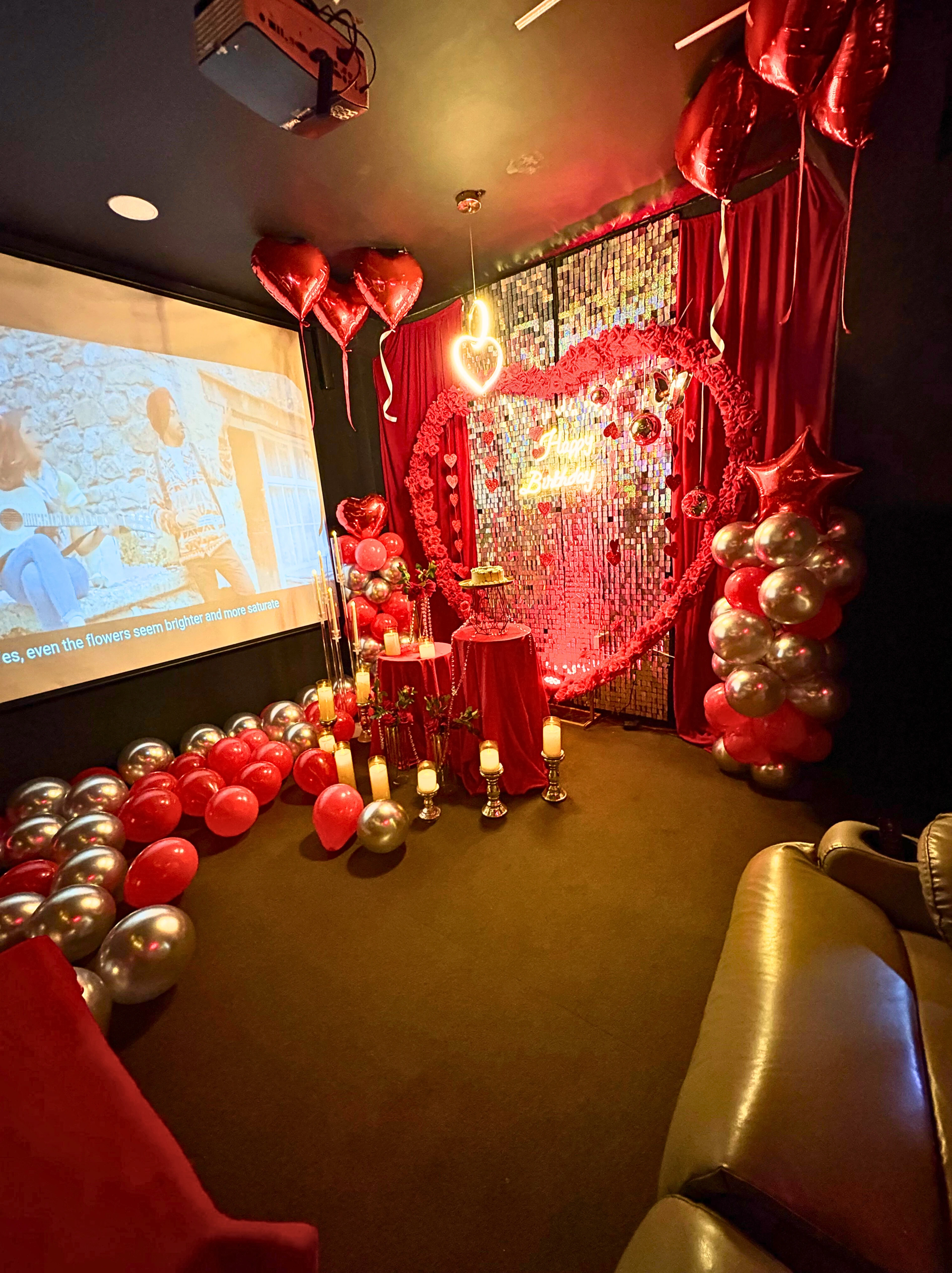 Grand birthday party inside private cinema with rose balloon arch, Happy Birthday neon sign and cake table