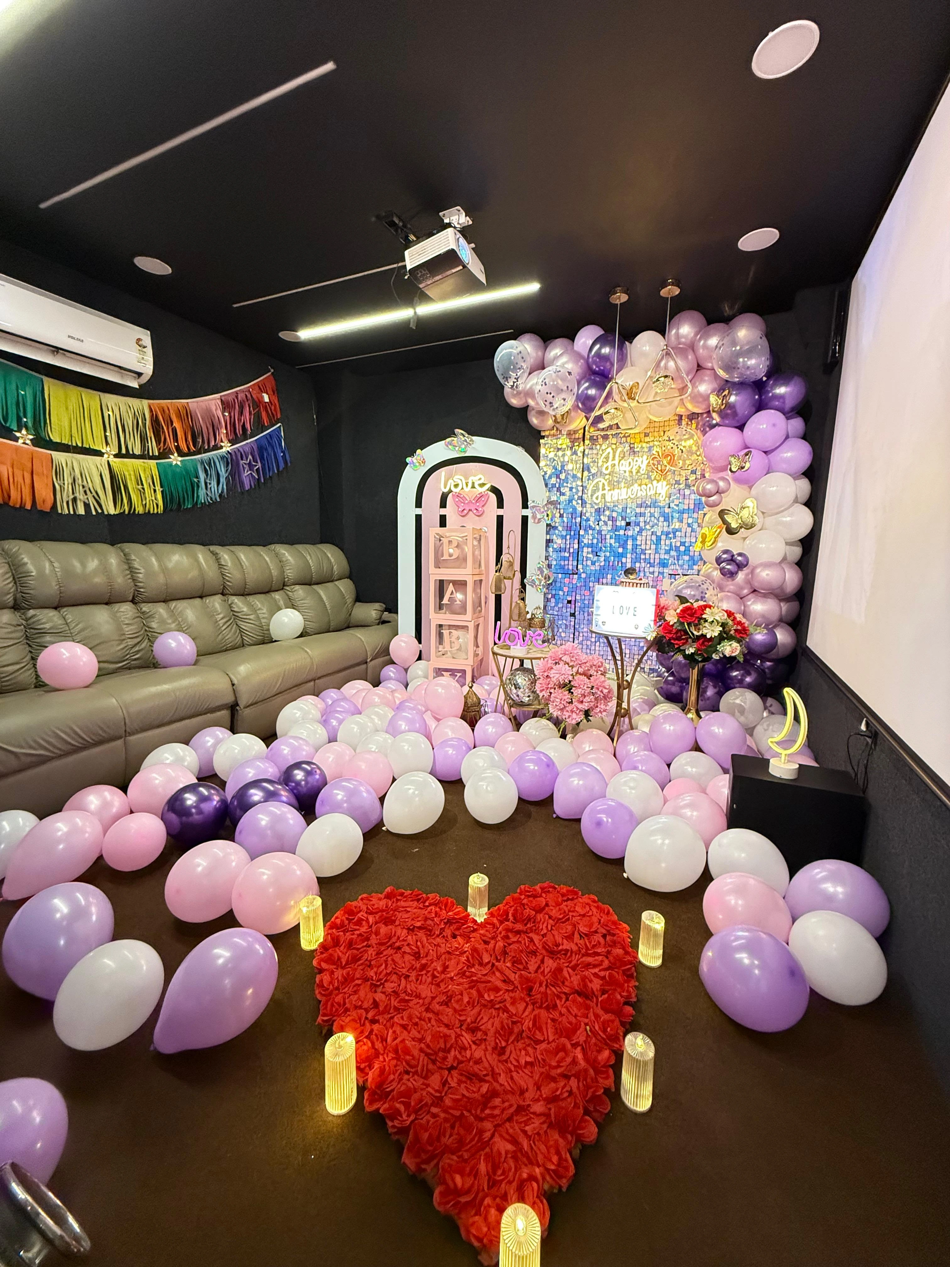 Anniversary private cinema suite with Happy Anniversary neon, rose petal heart and fairy-light decor